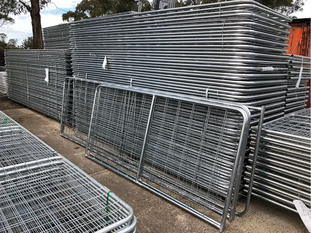 Stacks of galvanised rail farm gate leaves in a storage yard