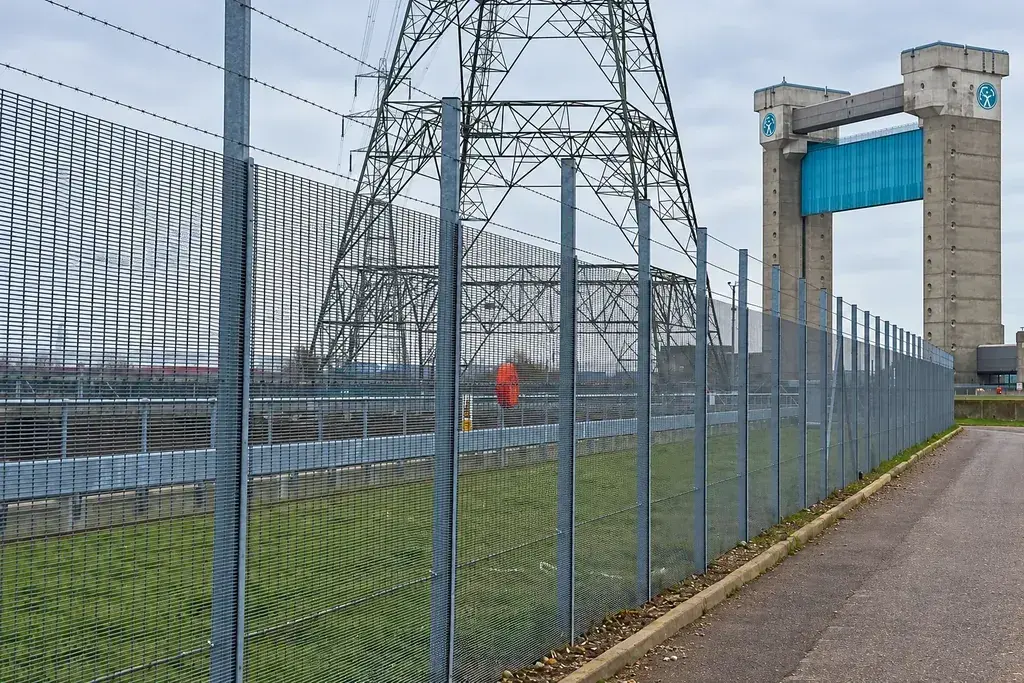 Grey mesh fence beside an infrastructure site and access path
