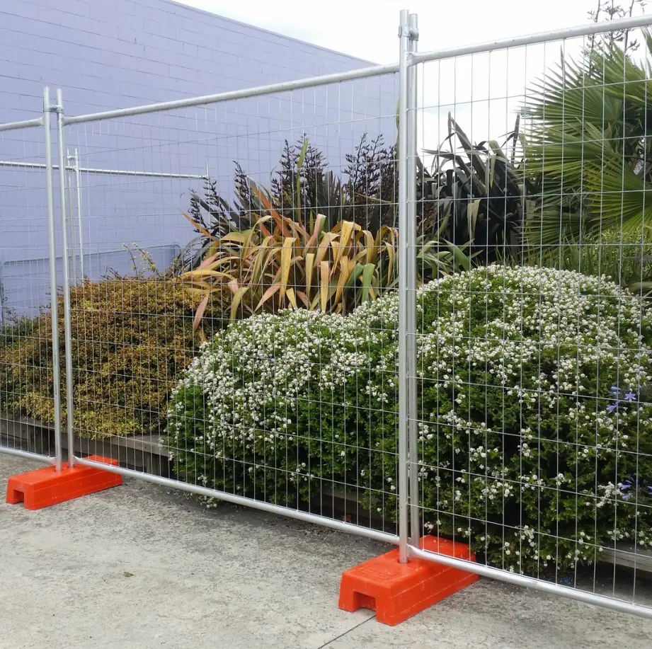 Relocatable mesh fence panels on weighted bases beside landscaping