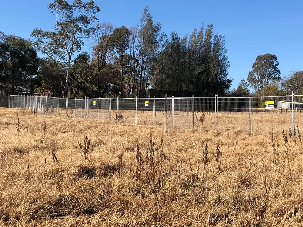 Reusable temporary mesh fence forming a long site boundary