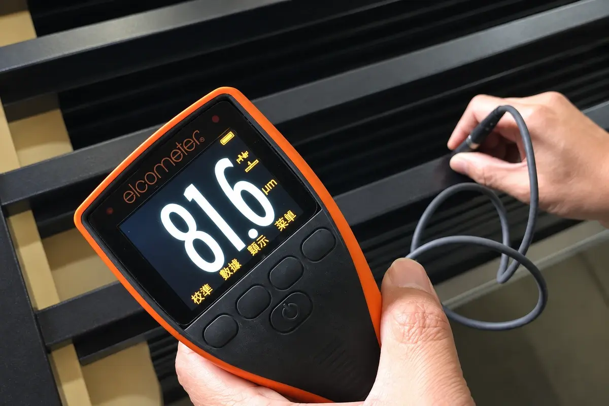 Handheld coating gauge checking a dark metal gate component