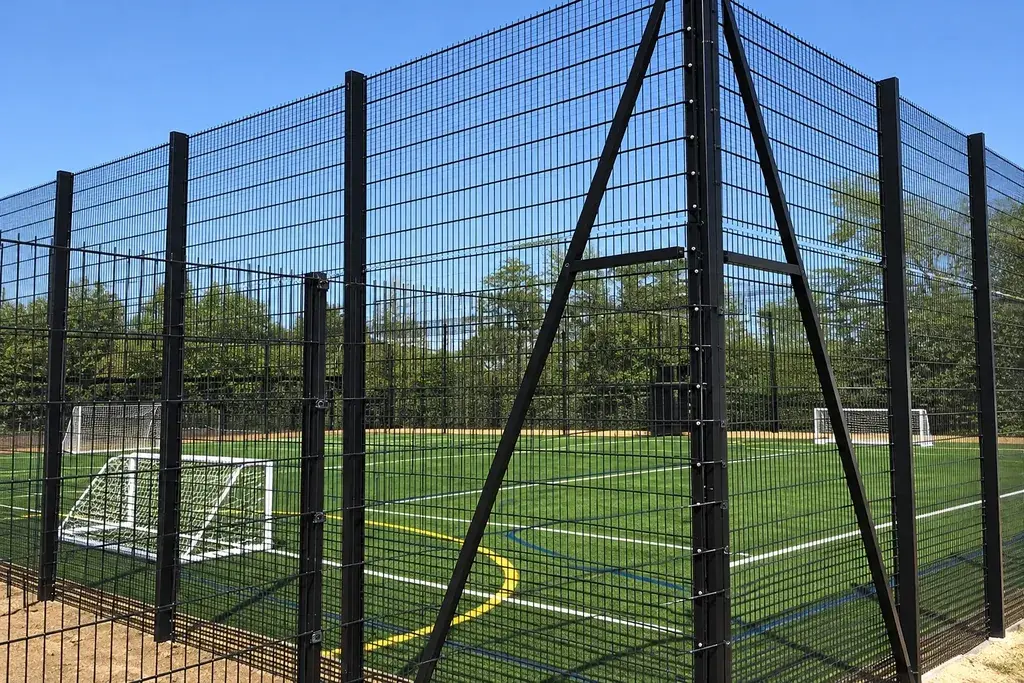 Mesh panels and corner posts around a school sports pitch