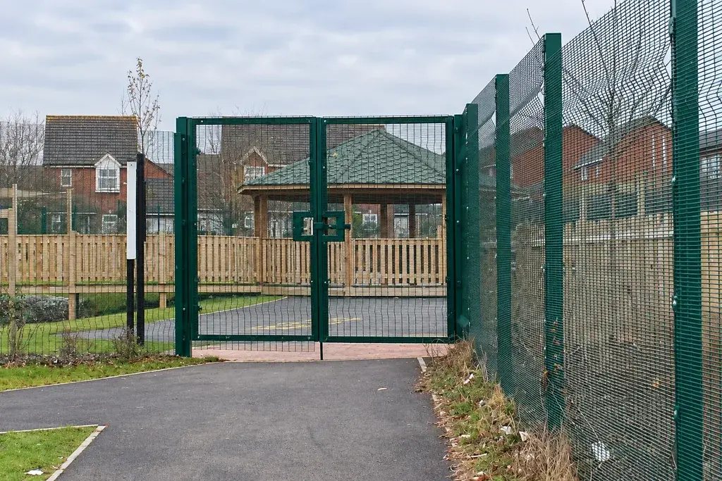 Green mesh gate adjoining profiled perimeter panels and posts