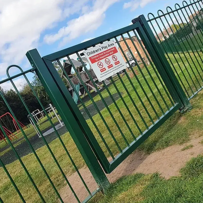 Green bow-top playground pedestrian gate beside matching fencing