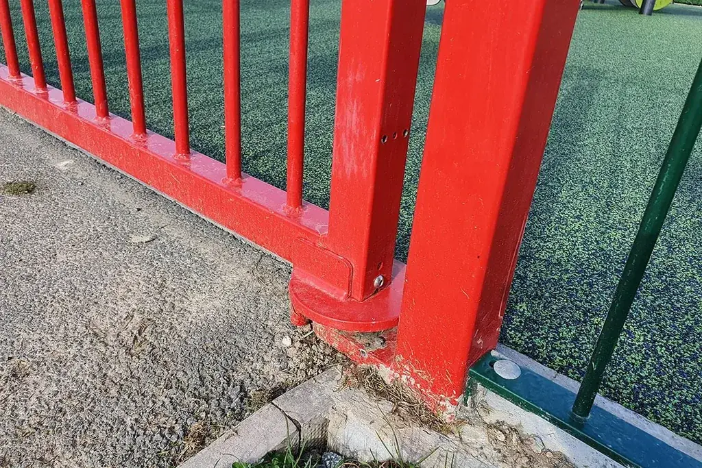 Lower closer assembly on a red playground gate