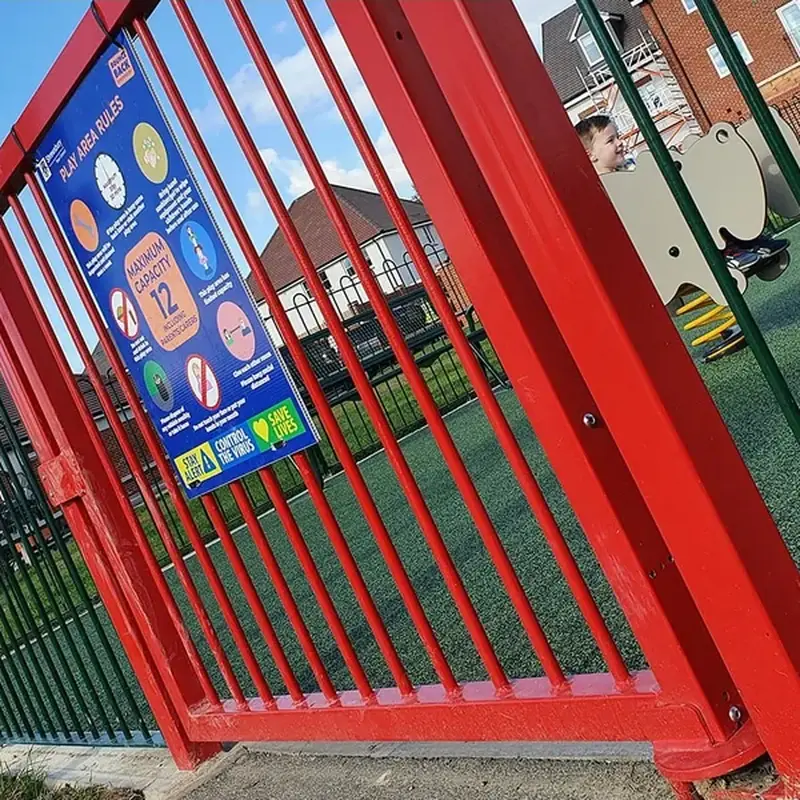 Red vertical-bar playground gate at an entrance