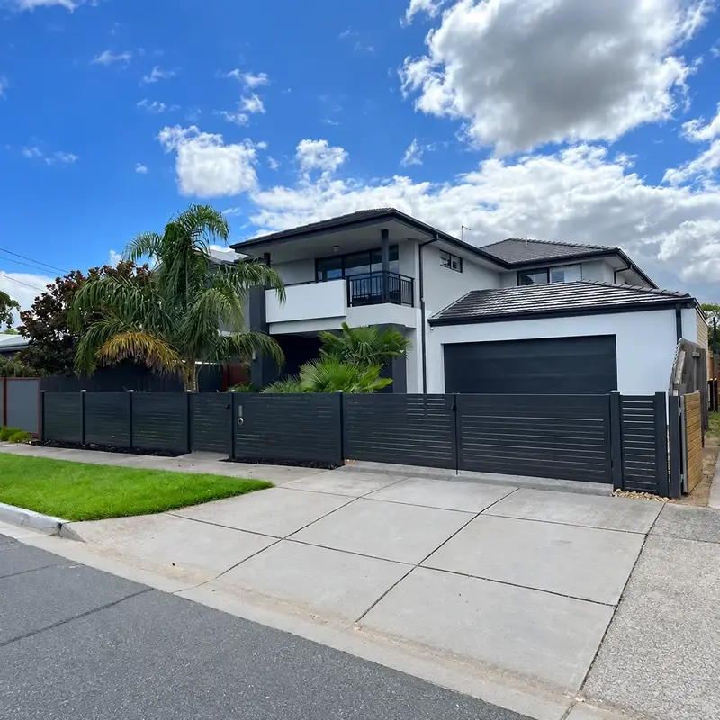 Dark sliding gate across a residential driveway