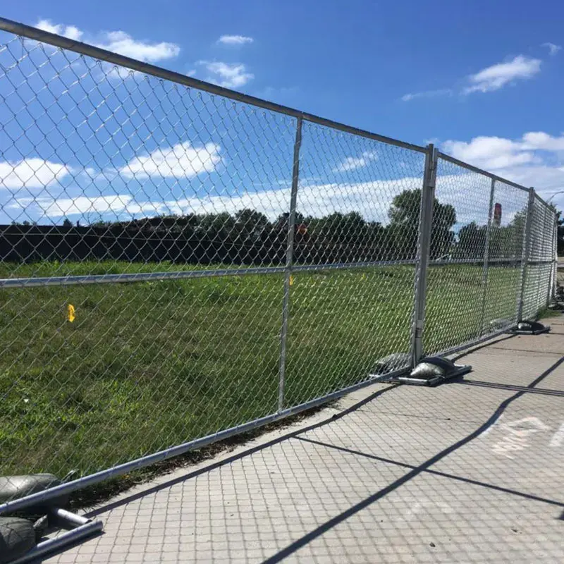 Temporary chain link panels with braces beside a grass boundary