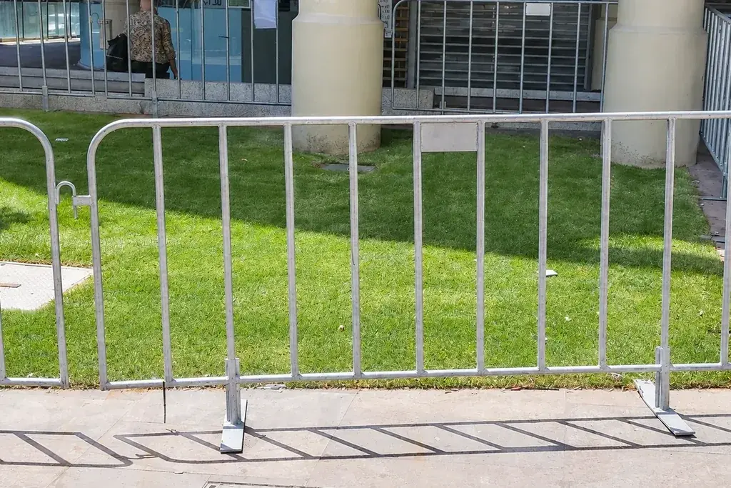 Galvanised pedestrian barriers with splayed feet beside a paved path