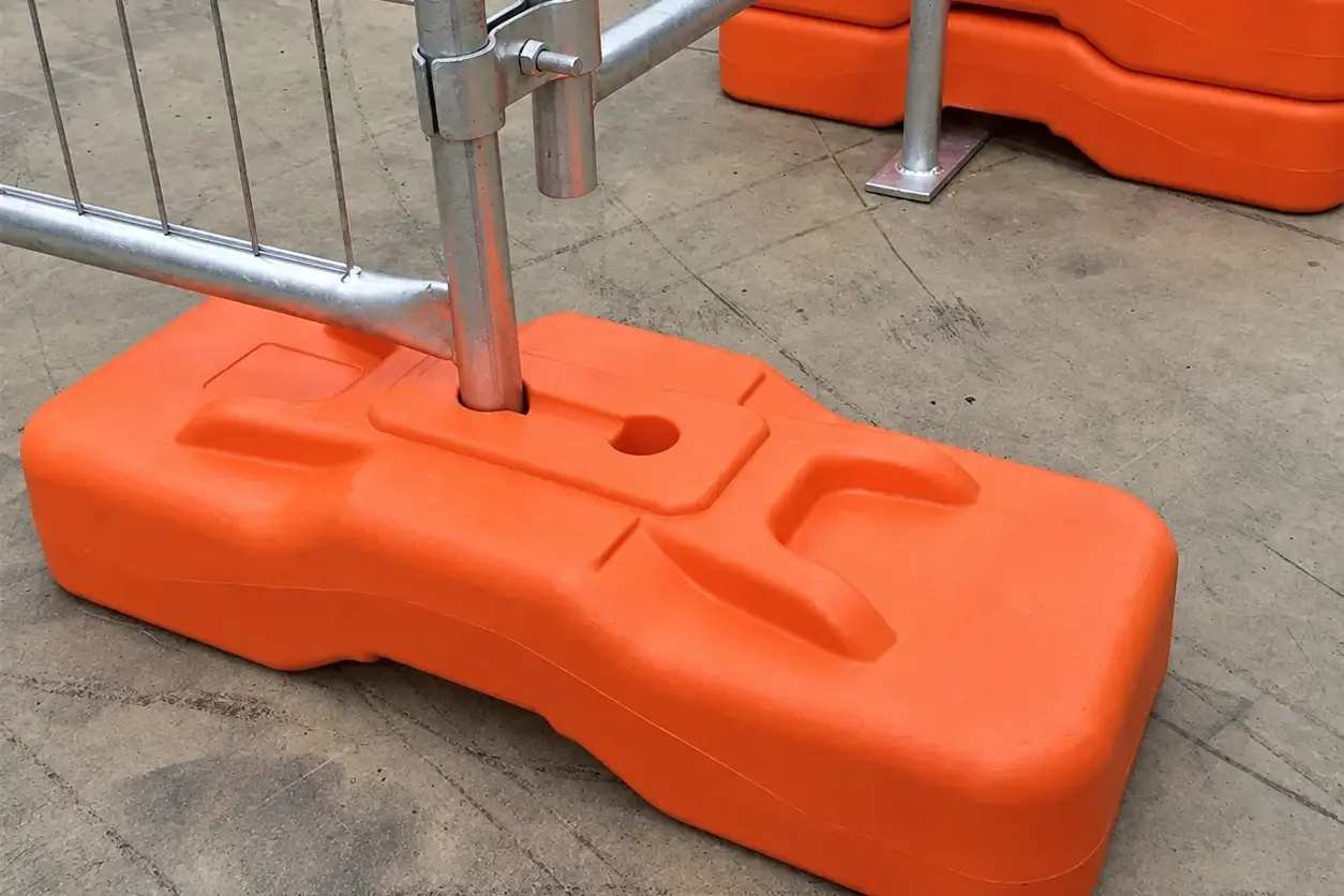 Orange temporary fence base with panel legs and a clamped support brace