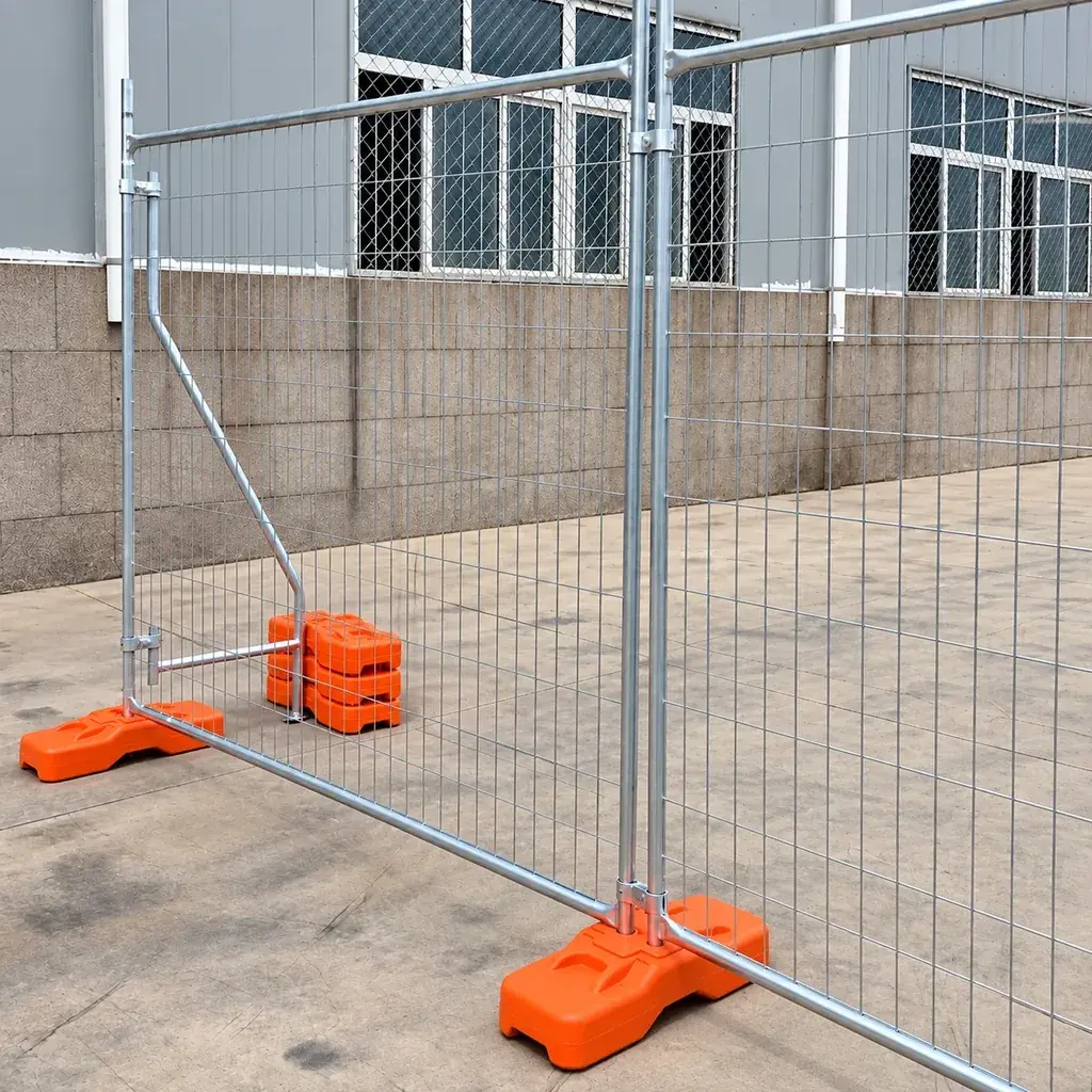 Temporary welded mesh panels on orange bases beside a warehouse