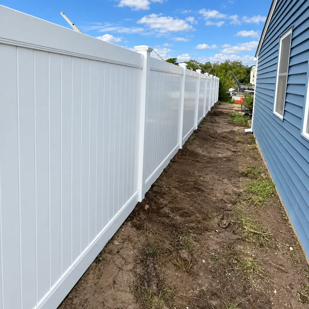 Tall white vinyl privacy fence along a narrow side yard