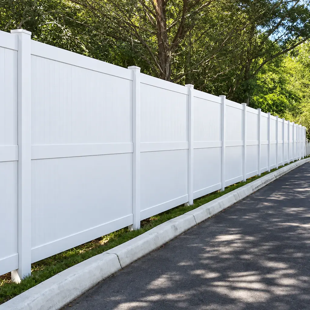 White vinyl privacy fence along a paved property boundary