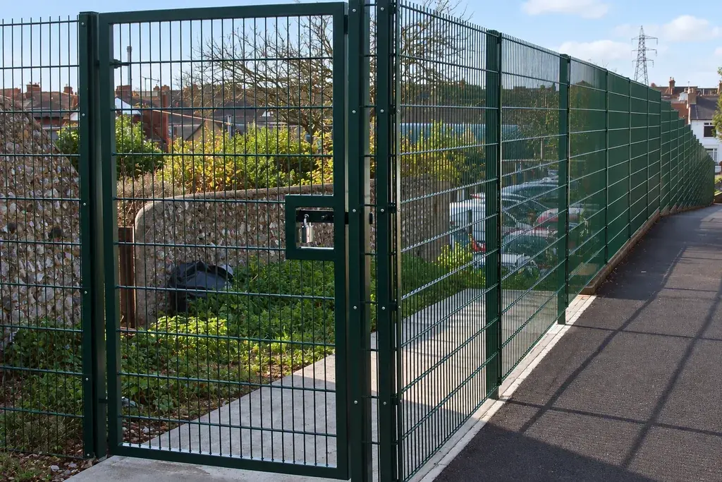 Dark framed mesh pedestrian gate beside a fenced path